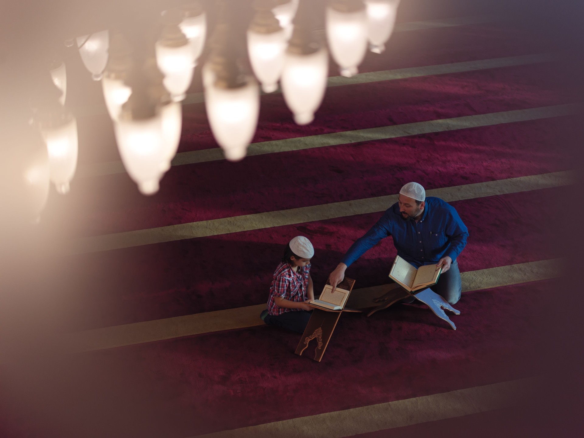 father and son in mosque praying and reading holly book quran together